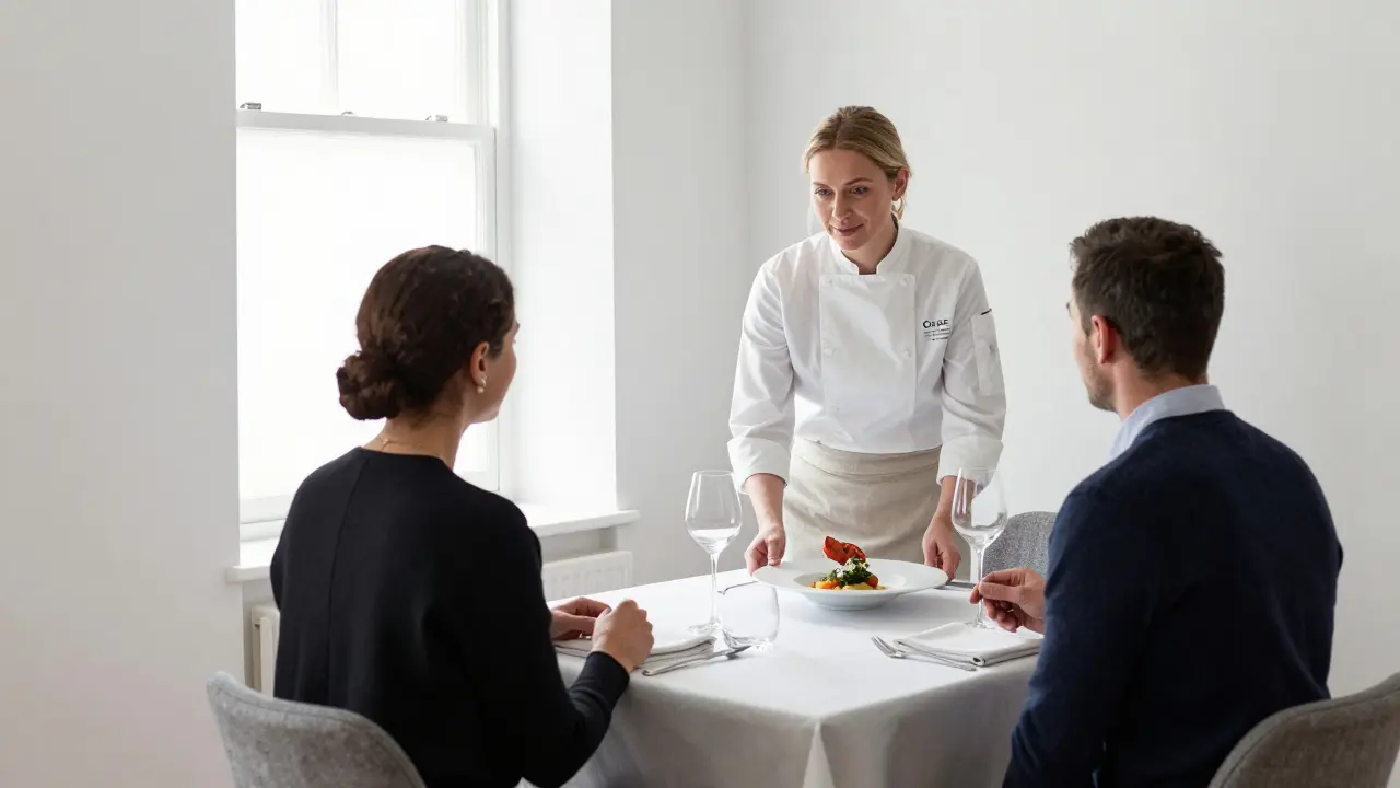 Chef Clare Smyth presenting a course to a couple in a minimalist white dining room at Core.